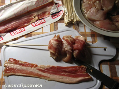 Обернуть беконом кусок курицы и нанизать на деревянную шпажку