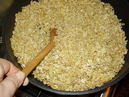 Бросьте порезанные орехи на глубокую (желательно чугунную) сковородку и немного их поджарьте